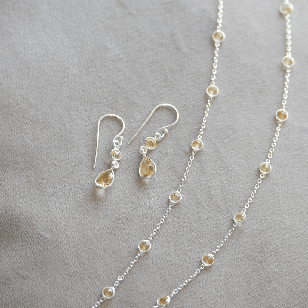 Silver necklace and earrings on a gray surface