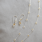 Silver necklace and earrings on a gray surface