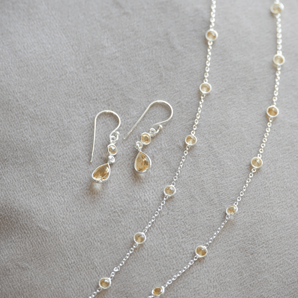 Silver necklace and earrings on a gray surface