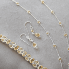 Silver jewelry set with teardrop-shaped stones on a gray background