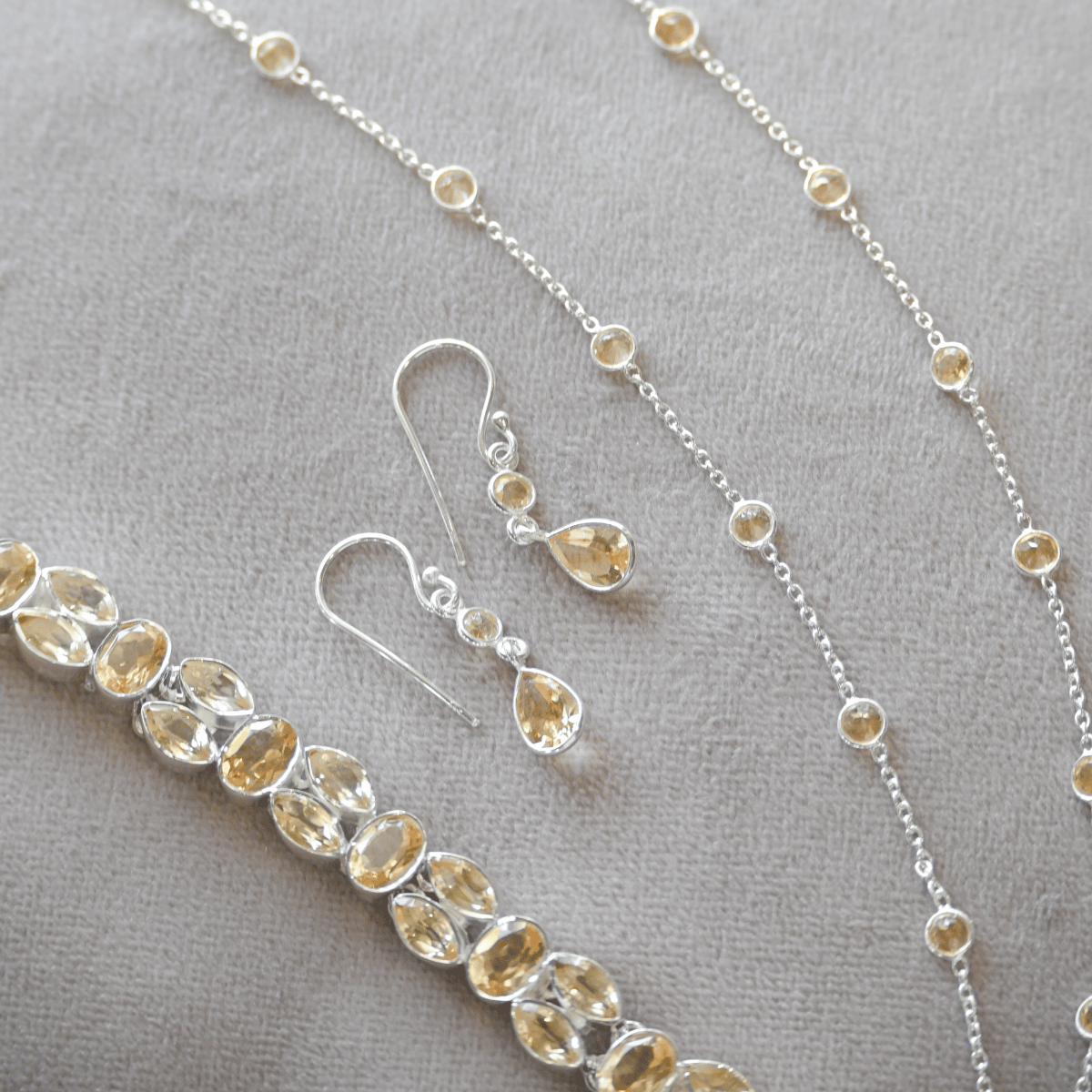 Silver jewelry set with teardrop-shaped stones on a gray background