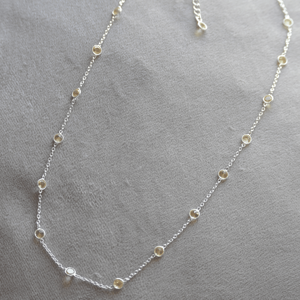 Silver necklace with small round beads on a gray surface