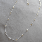 Silver necklace with small round beads on a gray surface