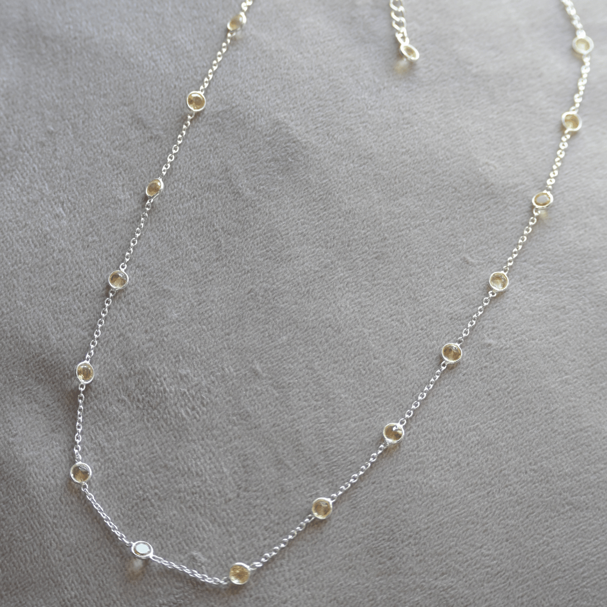 Silver necklace with small round beads on a gray surface