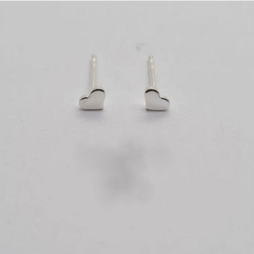 A pair of sterling silver stud earrings with a tiny heart design on a white background.