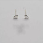 A pair of sterling silver stud earrings with a tiny heart design on a white background.