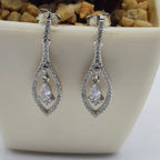A pair of sterling silver earrings with a diamond-shaped design, displayed in a white container.