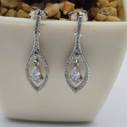 A pair of sterling silver earrings with a diamond-shaped design, displayed in a white container.