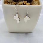 A pair of sterling silver drop earrings designed in the shape of Africa, displayed in a white vase with a textured background.