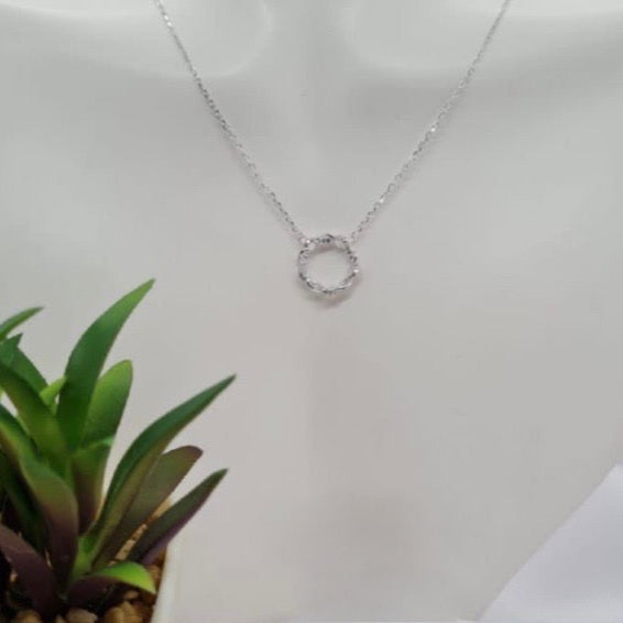 A sterling silver necklace with a cubic zirconia detail displayed on a mannequin.