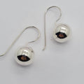A pair of sterling silver ball earrings with rounded hooks.