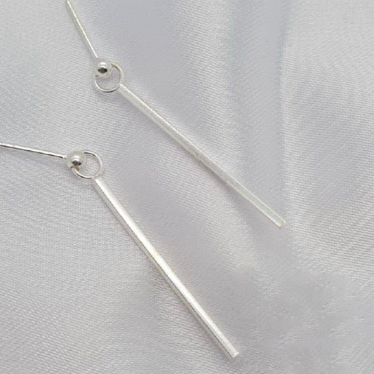 A pair of sterling silver bar drop earrings displayed on a white fabric surface.